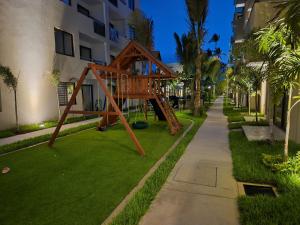 a playground in the grass next to a building at New Oceanfront Apartment in Mazatlán
