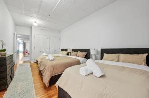 two beds in a bedroom with white walls and wood floors at Soho Fancy 4 Bedroom 2000 square feet Loft in New York