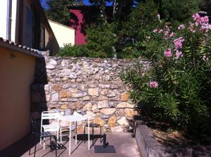 a stone wall with two chairs and a table in front of it at Maisonnette dans un parc du 18ème in Aix-en-Provence