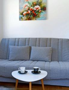 a living room with a couch with two cups on a table at Apartman CENTAR NEVA in Trebinje