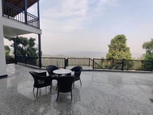 a table and chairs on a patio with a view at Charlie's Little Palace in Mukteshwar