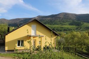 a yellow church with mountains in the background at Apartman Juka in Krasno Polje