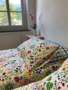 a bed with a flowered comforter and two pillows on it at Affittacamere Torrione in Venzone