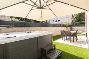 an outdoor hot tub with an umbrella in a yard at Apartman Monika in Split