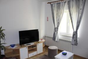 a living room with a tv and a window at Apartman Juka in Krasno Polje