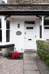 a white house with a white door and red flowers at Denecrest Guest House in Windermere