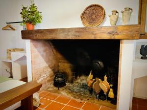 a brick fireplace with pots and vases on top of it at The Oak Tree Farm - Open Plan Layout by Portus Alacer in Rabaços
