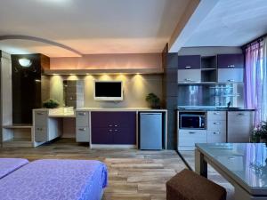 a room with a kitchen with purple cabinets and a table at Къща за гости Роси in Pomorie