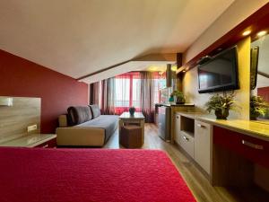 a hotel room with a red bed and a couch at Къща за гости Роси in Pomorie