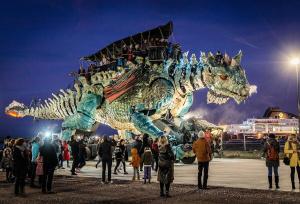 a crowd of people standing around a dragon float at La baraque bleriot beach in Sangatte +5 photos