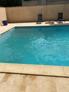 a swimming pool with two chairs in the water at Hotel - Restaurant de la Paix in Barbotan-les-Thermes