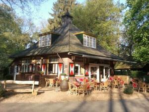 een groot huis met tafels en stoelen ervoor bij Minicamping de Lindehoef in Moergestel