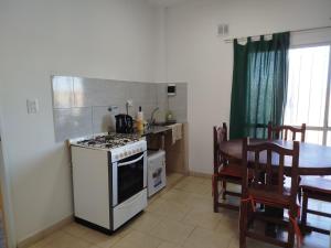 a kitchen with a stove and a table and a dining room at Apart Yo sur in Comodoro Rivadavia +3 photos