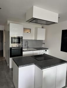 a kitchen with white cabinets and a black counter top at Petit Nid Pieds dans l'eau in Sausset-les-Pins