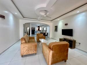 a living room with two couches and a flat screen tv at Azar Stays Diani in Diani Beach