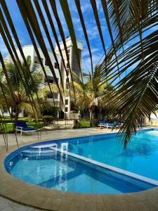 a large swimming pool with palm trees and a building at Azar Stays Diani in Diani Beach
