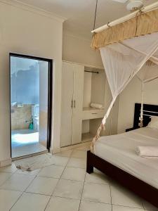a bedroom with a canopy bed and a bathroom at Azar Stays Diani in Diani Beach +53 photos