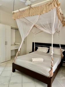 a bedroom with a bed with a canopy at Azar Stays Diani in Diani Beach