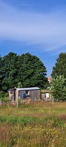 an old shed in a field with trees in the background at liberty - Urlaub im Zirkuswagen in Karstädt