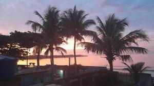 a group of palm trees in front of a sunset at Cantinho da Dê in Anchieta +6 photos