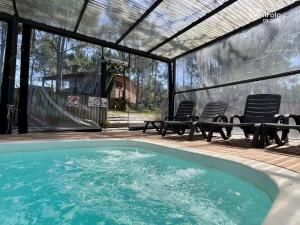 a swimming pool with two chairs and a table at Chimuelo Loft in Punta Del Diablo