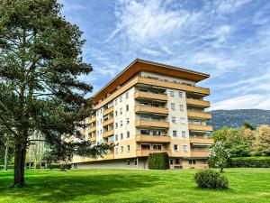 a large apartment building with a tree in a field at RIOpartment Ossiacher See in Bodensdorf