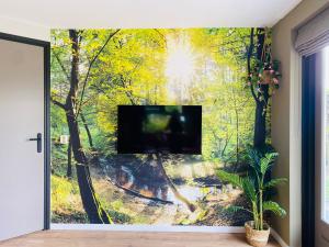 a tv in a room with a forest mural at Morning Glory Huisje Salvia in Beekbergen
