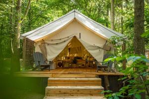 a tent in the woods with a wooden deck at Kaluna Glamp Jungle in Swaderki