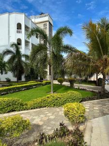 a white building with palm trees in front of it at Clalem Condos Diani Beach in Diani Beach