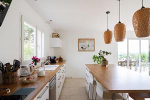 オーズヴィル・トロザーヌにあるMaison avec piscine, au calme près de Toulouseの白いキャビネットと木製のカウンタートップを備えたキッチン
