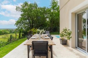 オーズヴィル・トロザーヌにあるMaison avec piscine, au calme près de Toulouseのパティオにある木製のテーブルと椅子