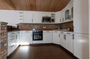 cocina con armarios blancos y techo de madera en Bungalow zum Wohlfühlen, en Oranienburg