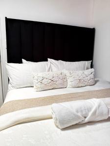 1 cama con cabecero negro y 2 almohadas en Mayvlei Luxury CBD apartment, en Windhoek