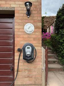 a clock on the side of a house with a pay phone at Yew Tree Cottage - walks from the door in Colwall