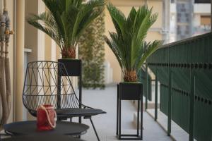 een zwarte stoel en twee palmbomen op een balkon bij Namuri Catania Centro in Catania