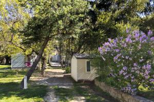 a small house in a yard with purple flowers at Camping 3* Les Templiers in Roquebillière