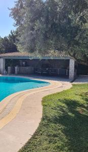 a swimming pool next to a house with a building at Villa Dalousa Retreat - Porto Heli in Porto Heli