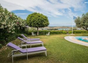 a group of chairs sitting in the grass by a pool at Villa Dalousa Retreat - Porto Heli in Porto Heli