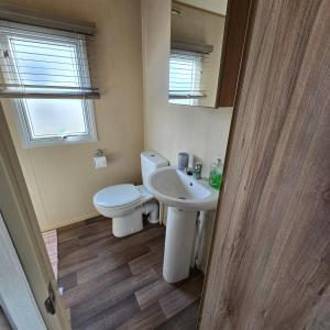 a bathroom with a white toilet and a sink at Thornwick bay Yellowhammer 28 in Flamborough +9 photos