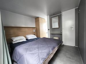 a bedroom with a large bed with a wooden headboard at Mobil home premium plage et piscine domaine la yole proche valras plage in Vendres