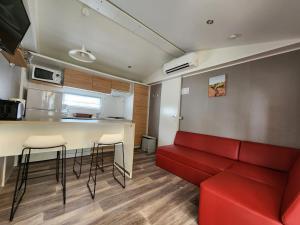 a living room with a red couch and a kitchen at Mobil home premium plage et piscine domaine la yole proche valras plage in Vendres