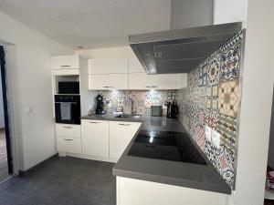 a kitchen with white cabinets and a black counter top at Maison cosy climatisée avec jardin in Aulnay-sous-Bois