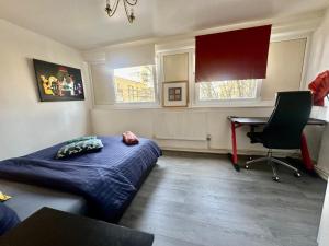 una camera da letto con un letto, una scrivania e due finestre di Renovu Houses in East London a Londra