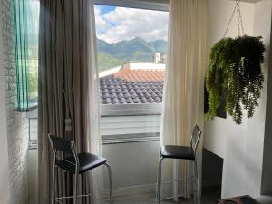 a room with two chairs and a window with a view at Apto moderno - Ao lado Weg - Próx Via verde in Jaraguá do Sul