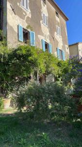 a building with blue shutters and bushes in front of it at La casa di Carlotta in Usi
