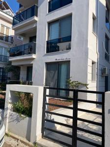 a white apartment building with a black fence at Mama Saggio Home in Fethiye