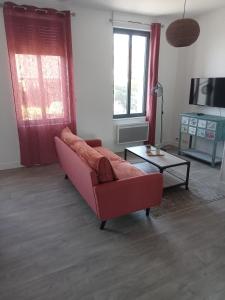 a living room with a red couch and a table at Les Halles centre ville parking en option in Étretat