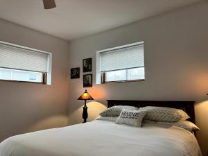 1 dormitorio con 1 cama con lámpara y 2 ventanas en Luxury, Convenience and Comfort Near Acadia!, en Ellsworth