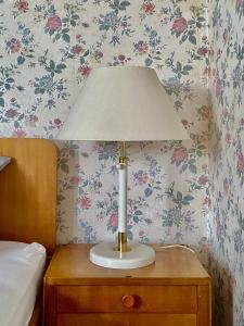 a lamp on a night stand next to a bed at Estelada Boarding Houses Oberhaching in Oberhaching