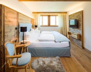 ein Hotelzimmer mit einem Bett, einem Tisch und einem Stuhl in der Unterkunft Haller's Geniesserhotel in Mittelberg